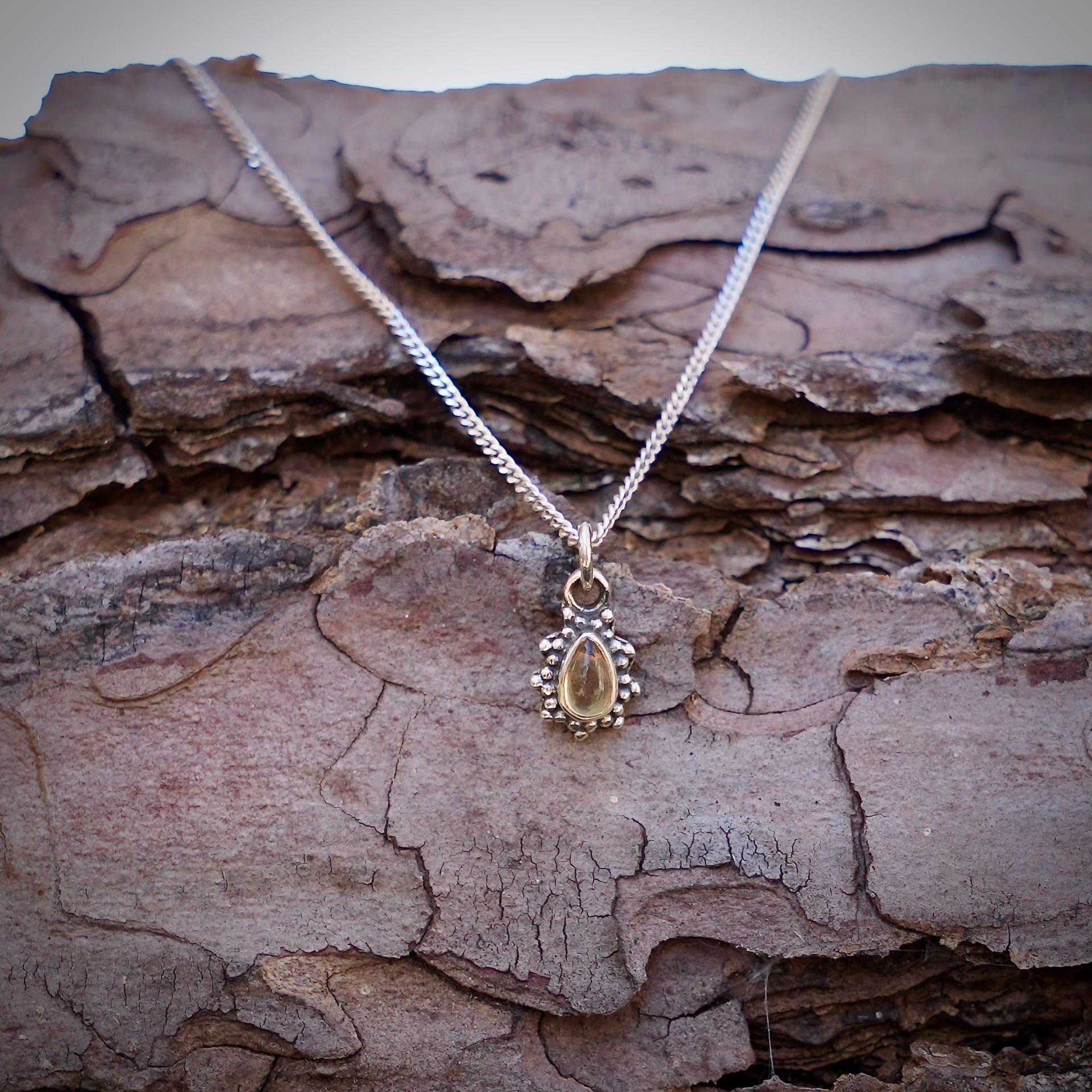 Zilveren hanger met citrien in druppelvorm met sierlijke zilveren parelrand