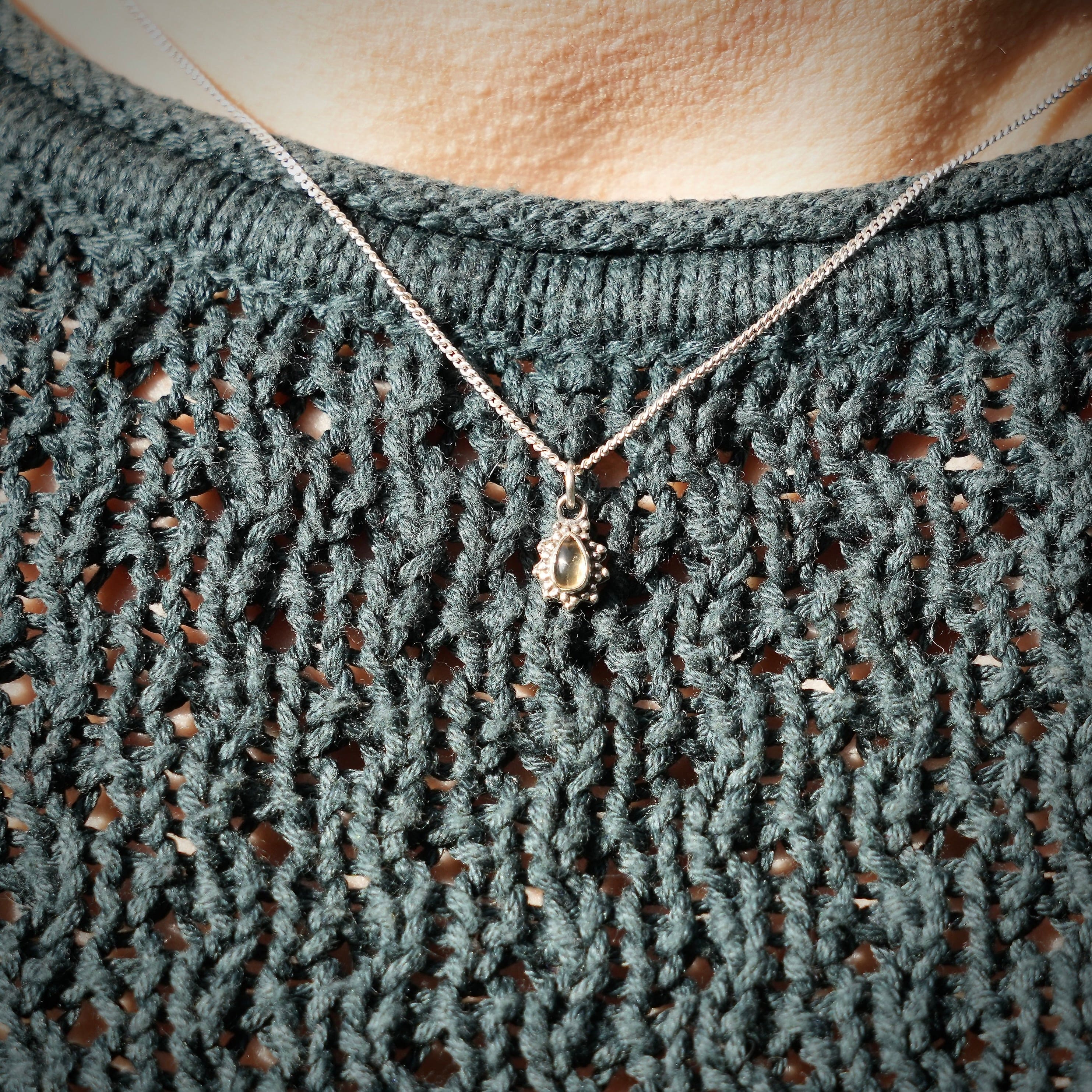 Persoon met Zilveren hanger met citrien in druppelvorm met sierlijke zilveren parelrand