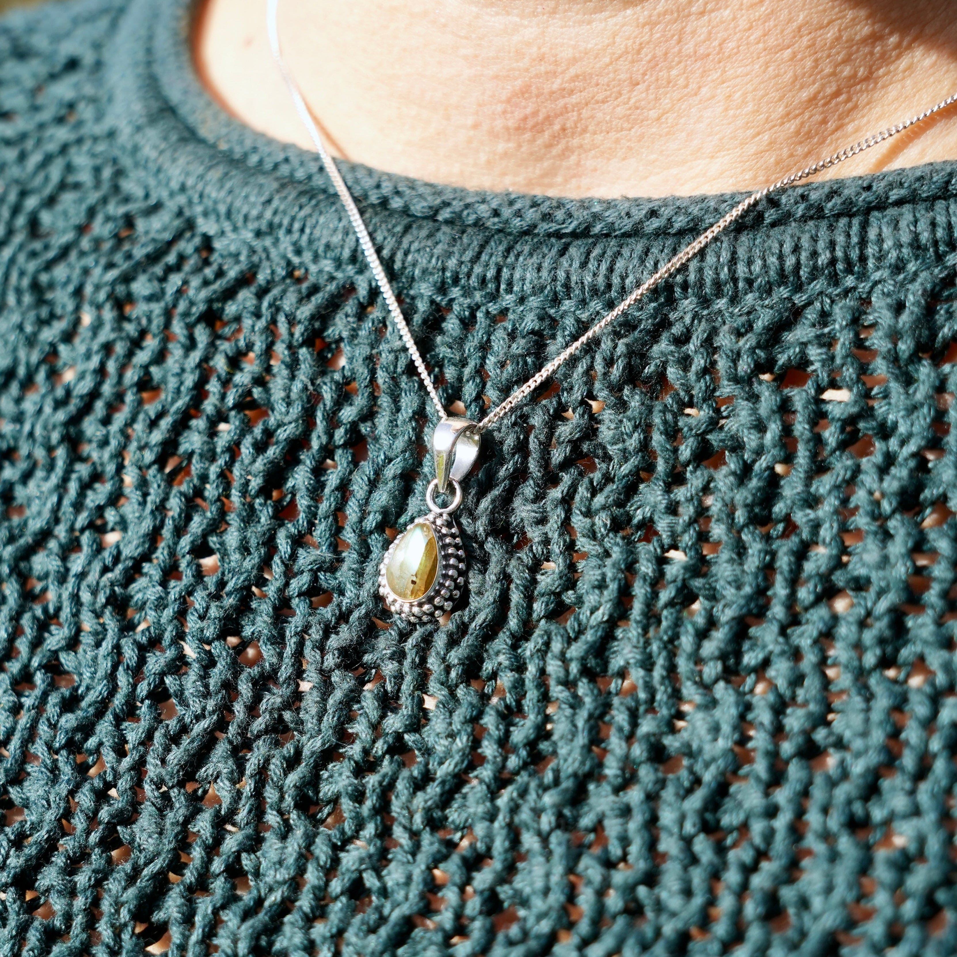 Persoon met een Zilveren hanger met labradoriet in druppelvorm met parelrand