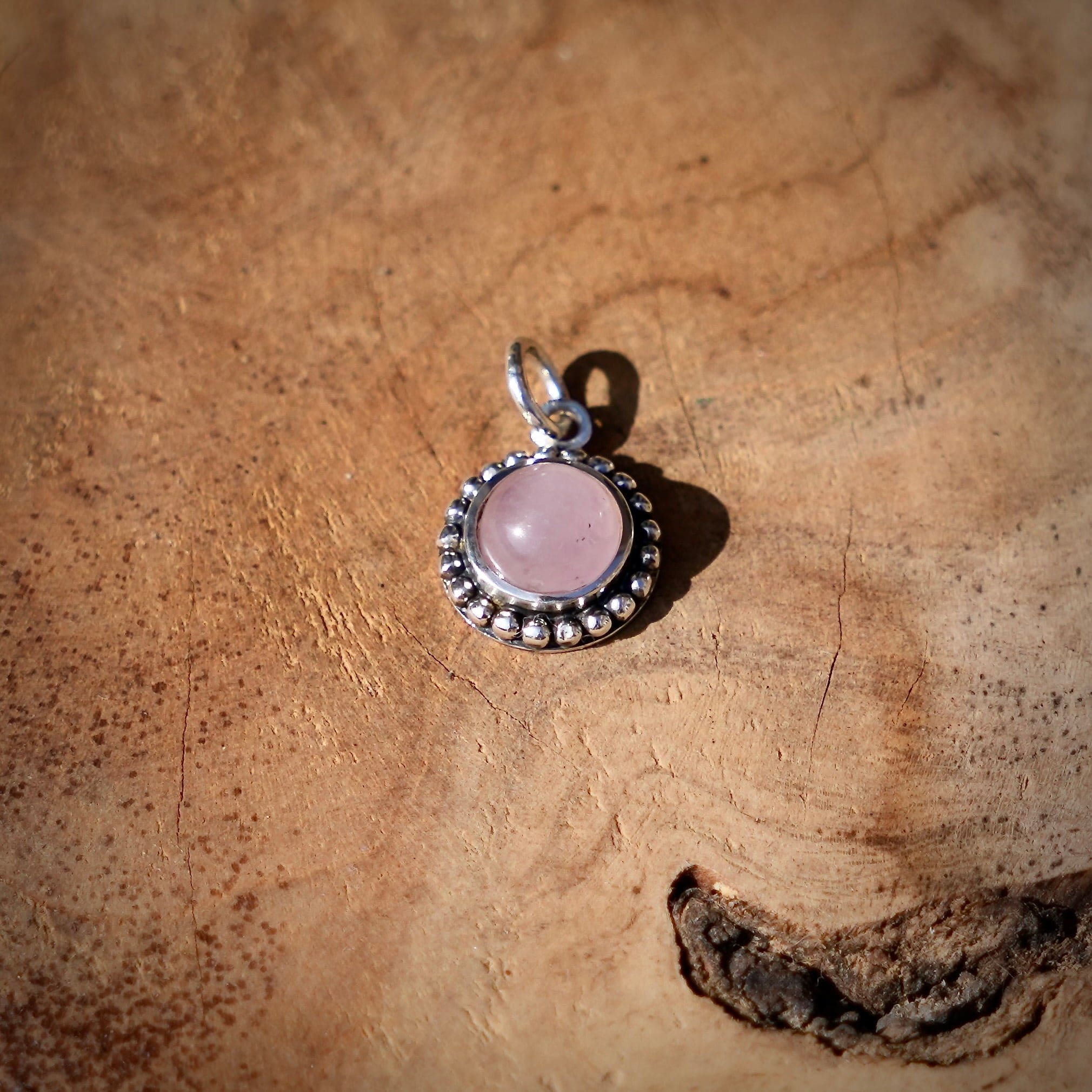 Hanger van 925 zilver met rozenkwarts op een houten ondergrond