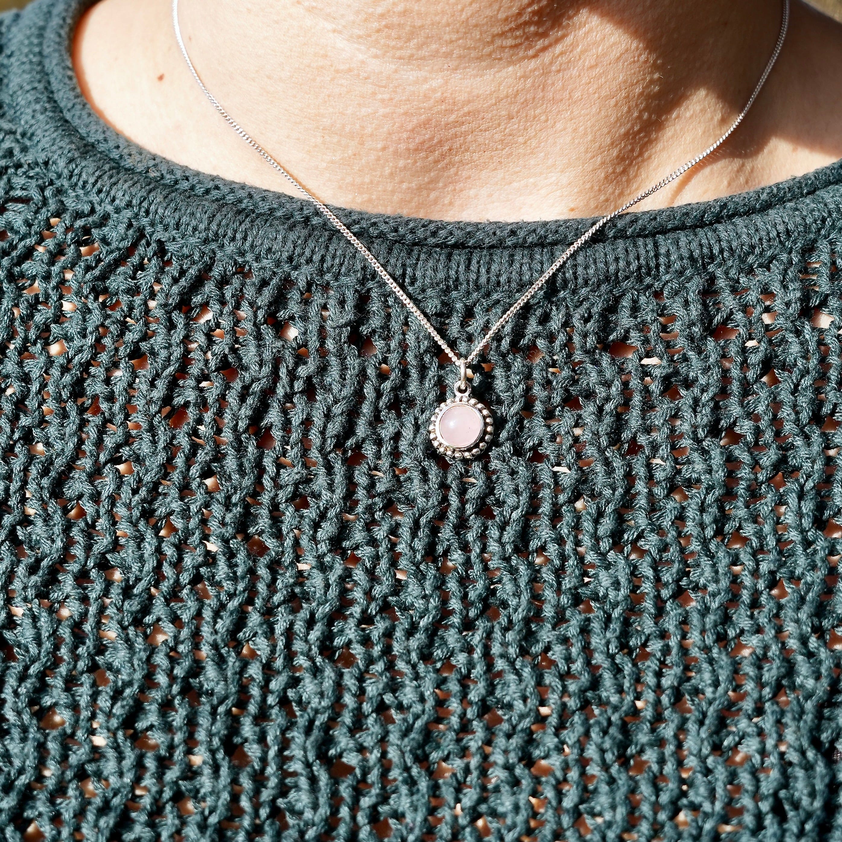 persoon met halsketting met Hanger van zilver met rozenkwarts over een groene trui