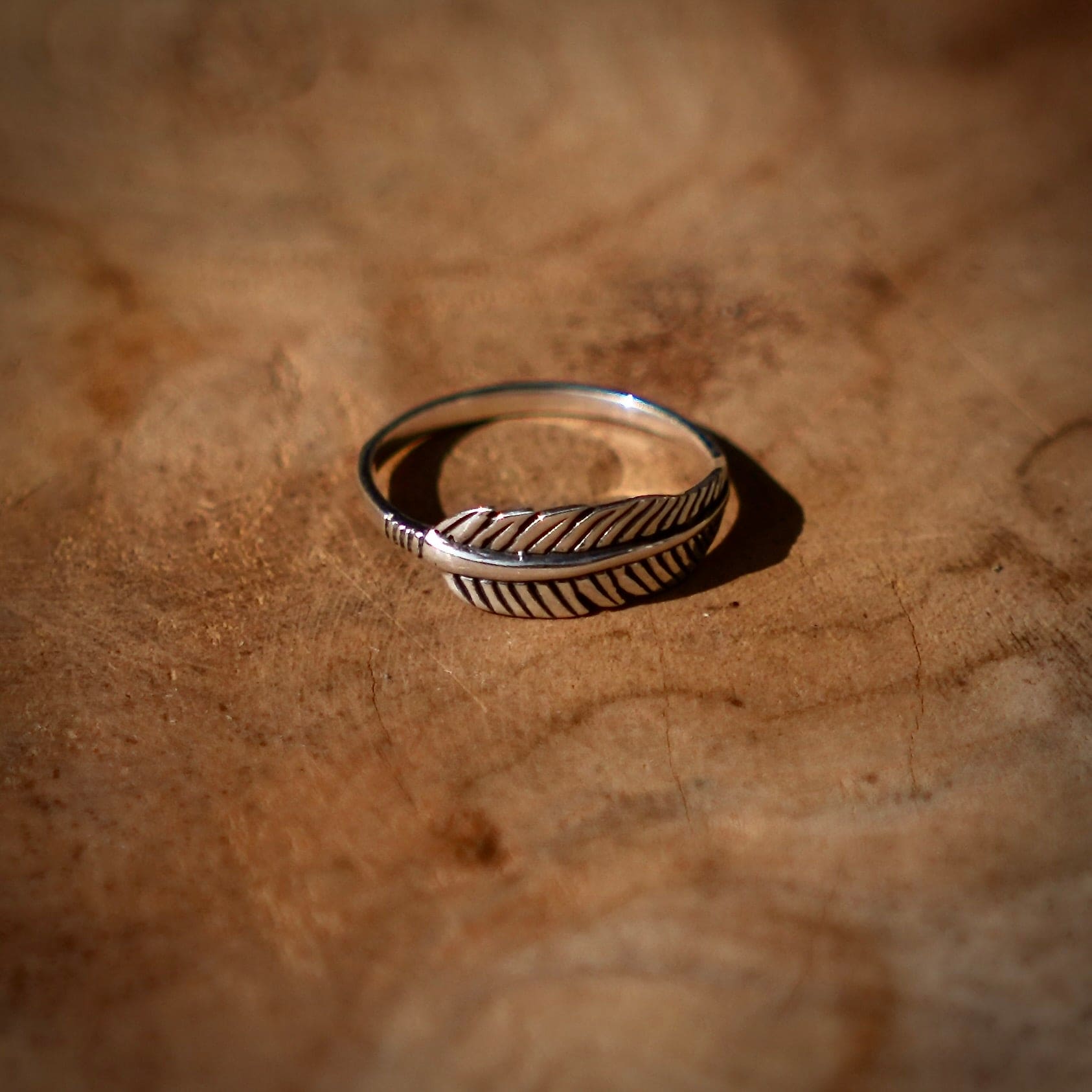 zilveren ring in de vorm van een veer op een houten ondergrond