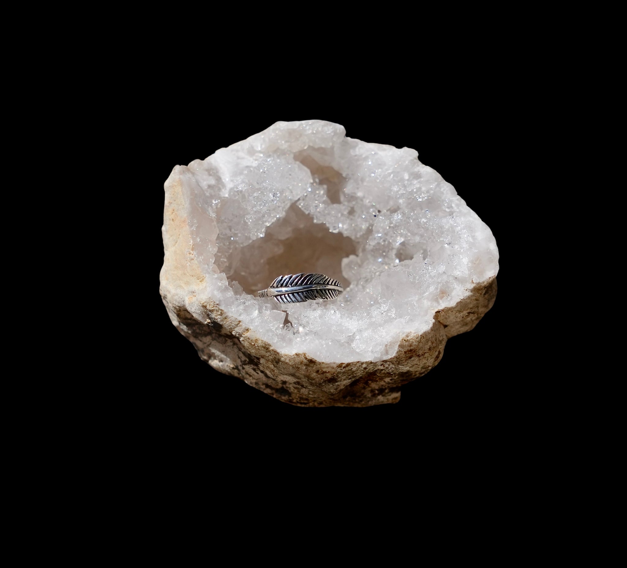 zilveren ring in de vorm van een veer, gefotografeerd in een bergkristal geode