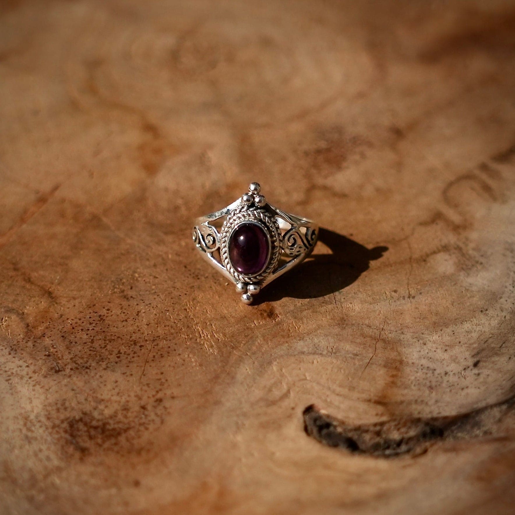 Sierlijke opengewerkte ring met Amethist op houten ondergrond