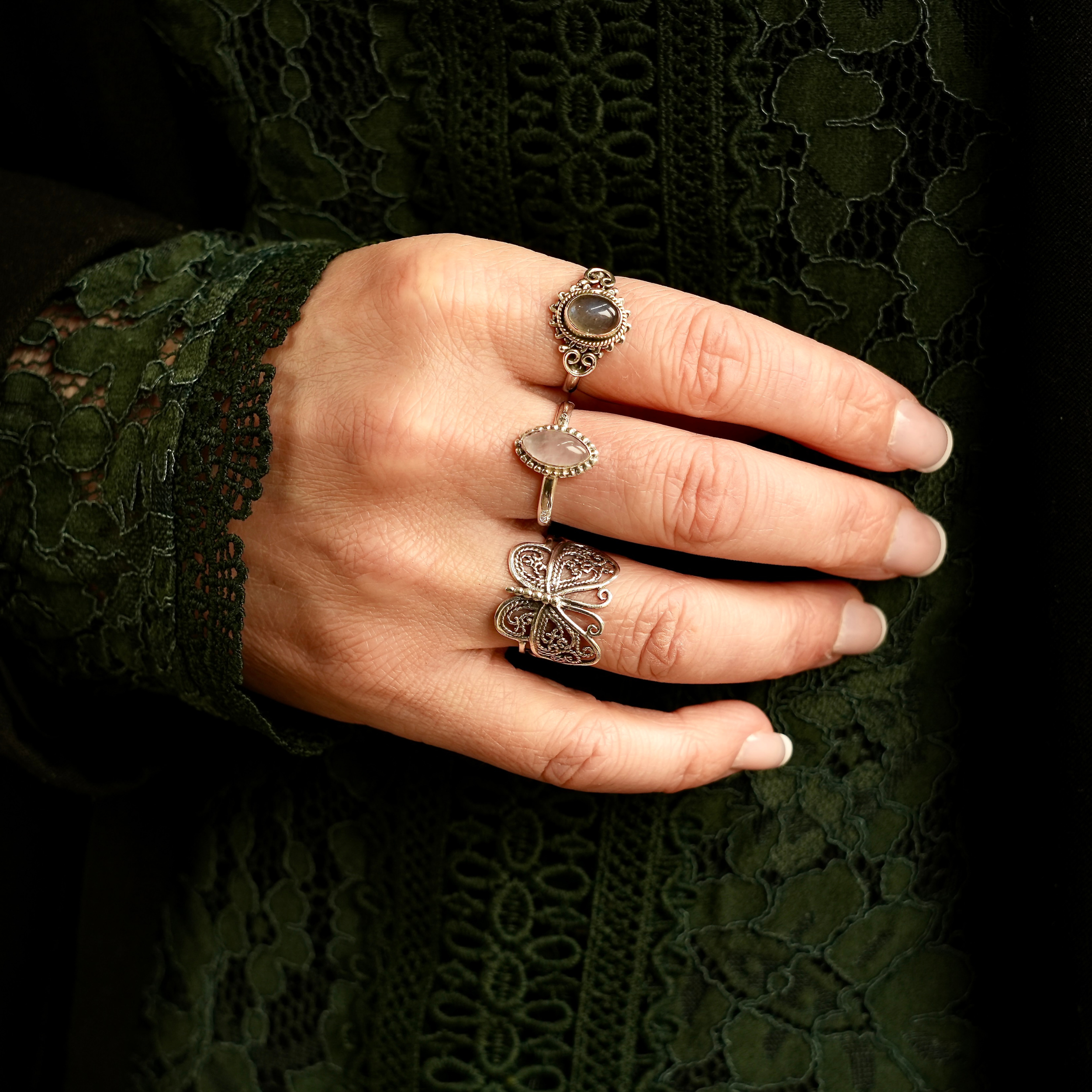 Drie ringen aan hand waarvan 1 met labradoriet, een met rozenkwarts en 1 met een vlinder