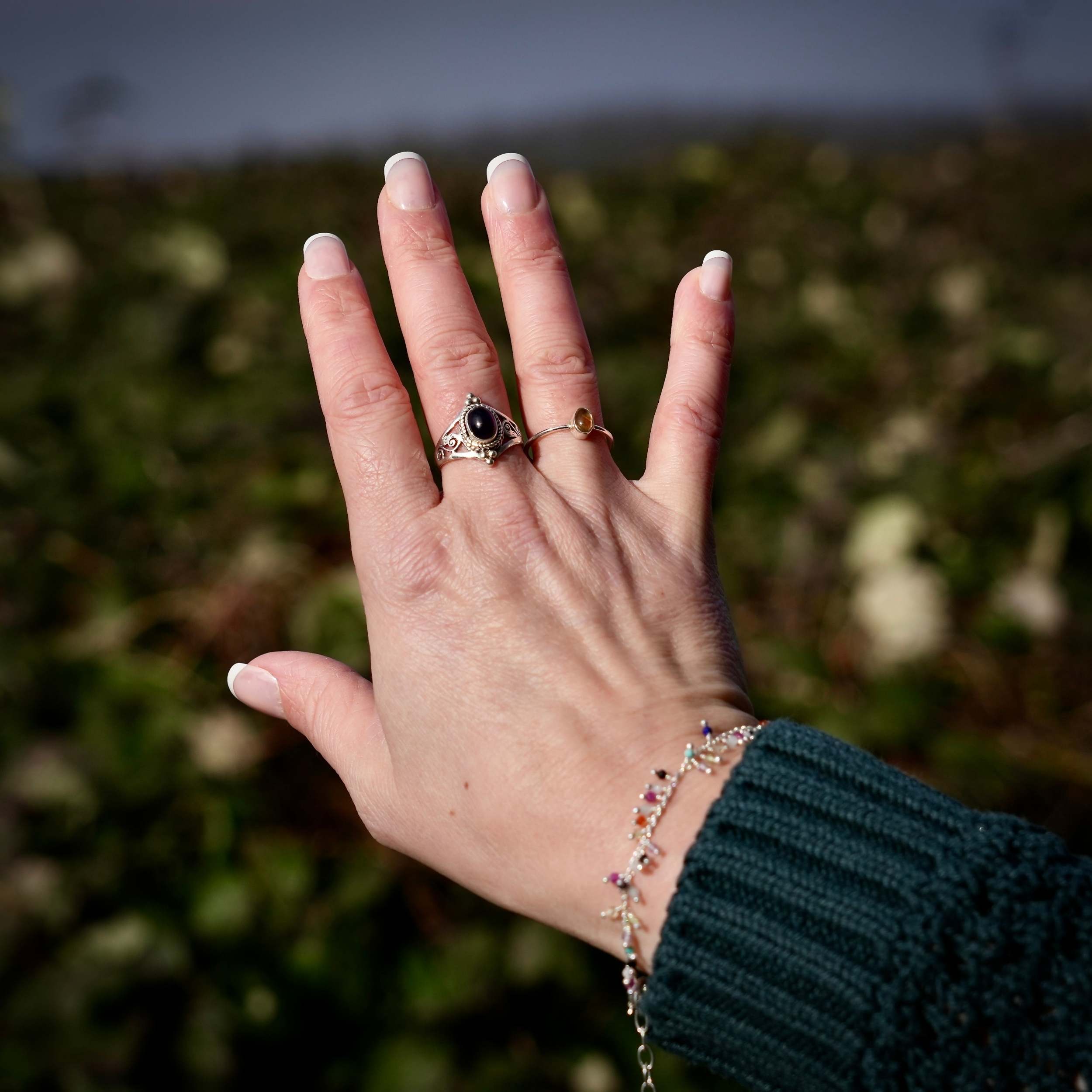Sfeerfoto van hand met zilveren ring Citur en armband op natuurlijke achtergrond - Juwelen uit de Natuur
