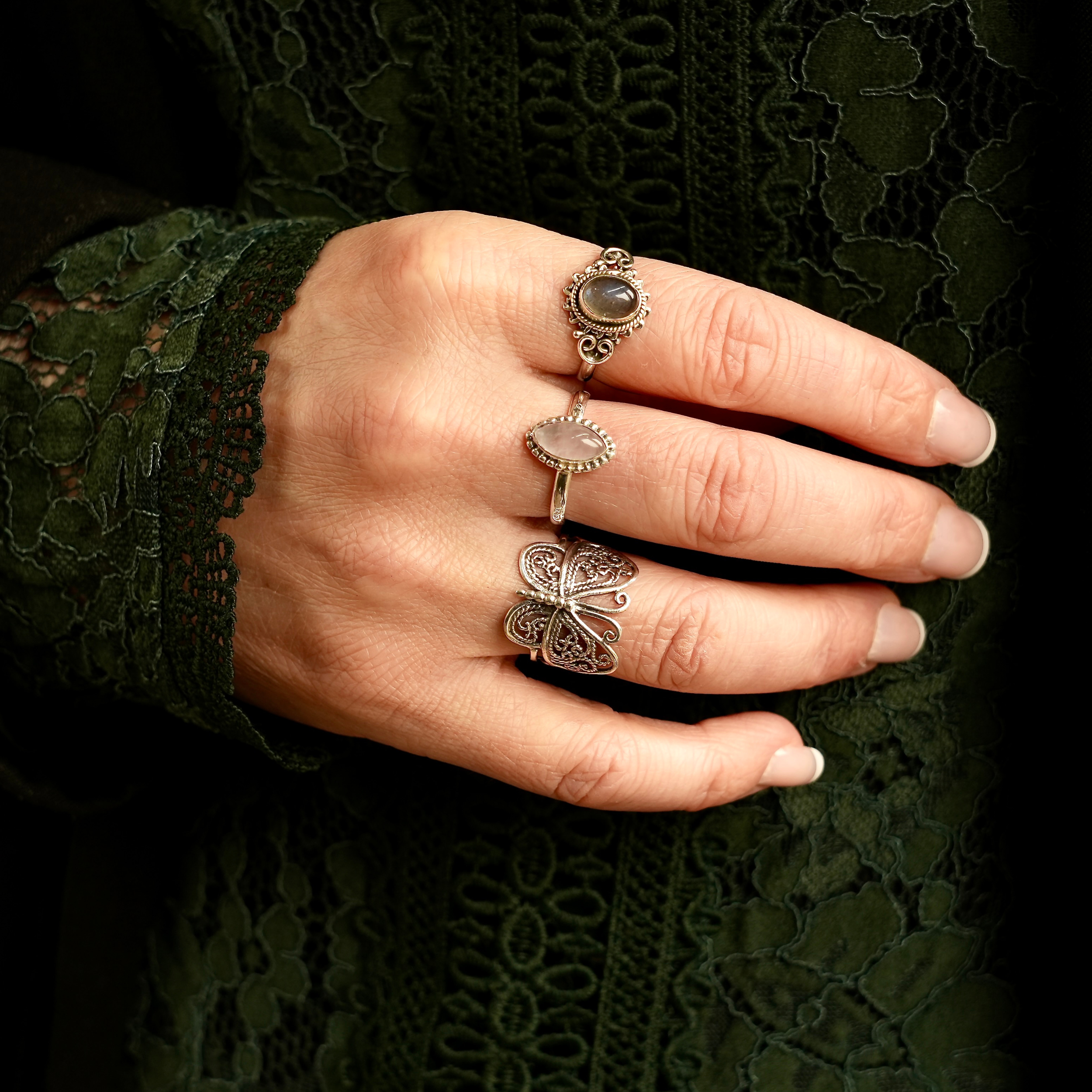 hand met drie ringen in de vorm van labradoriet, rozenkwarts en vlindervorm