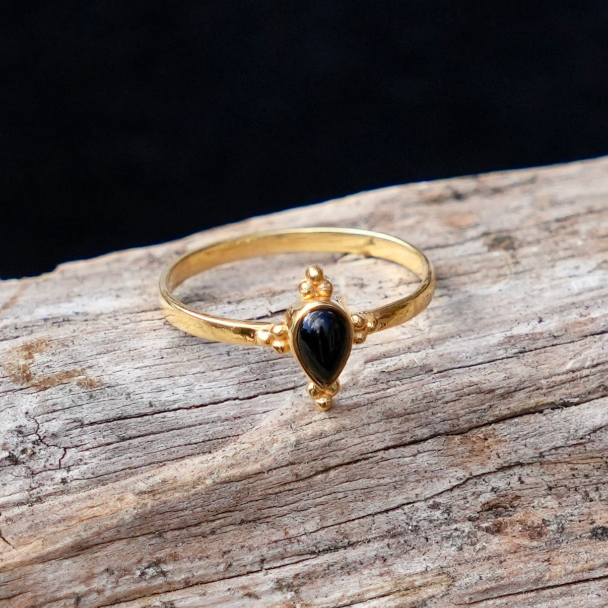 goldplated ring met kleine zwarte onyx in druppelvorm en wat drops rondom de druppel